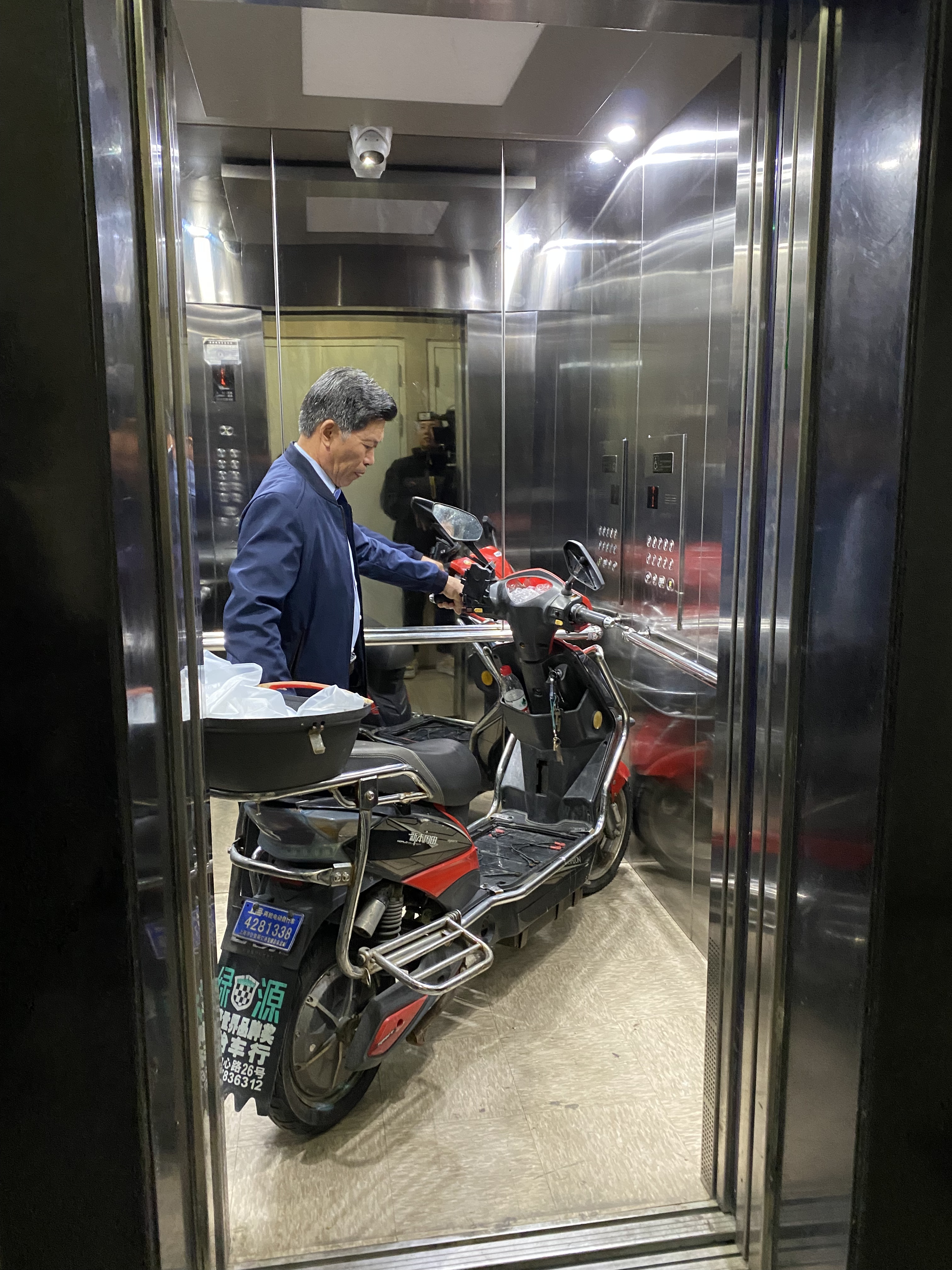 九亭家园二期一名居民推着电瓶车进入电梯准备上楼时,电梯内警示灯亮