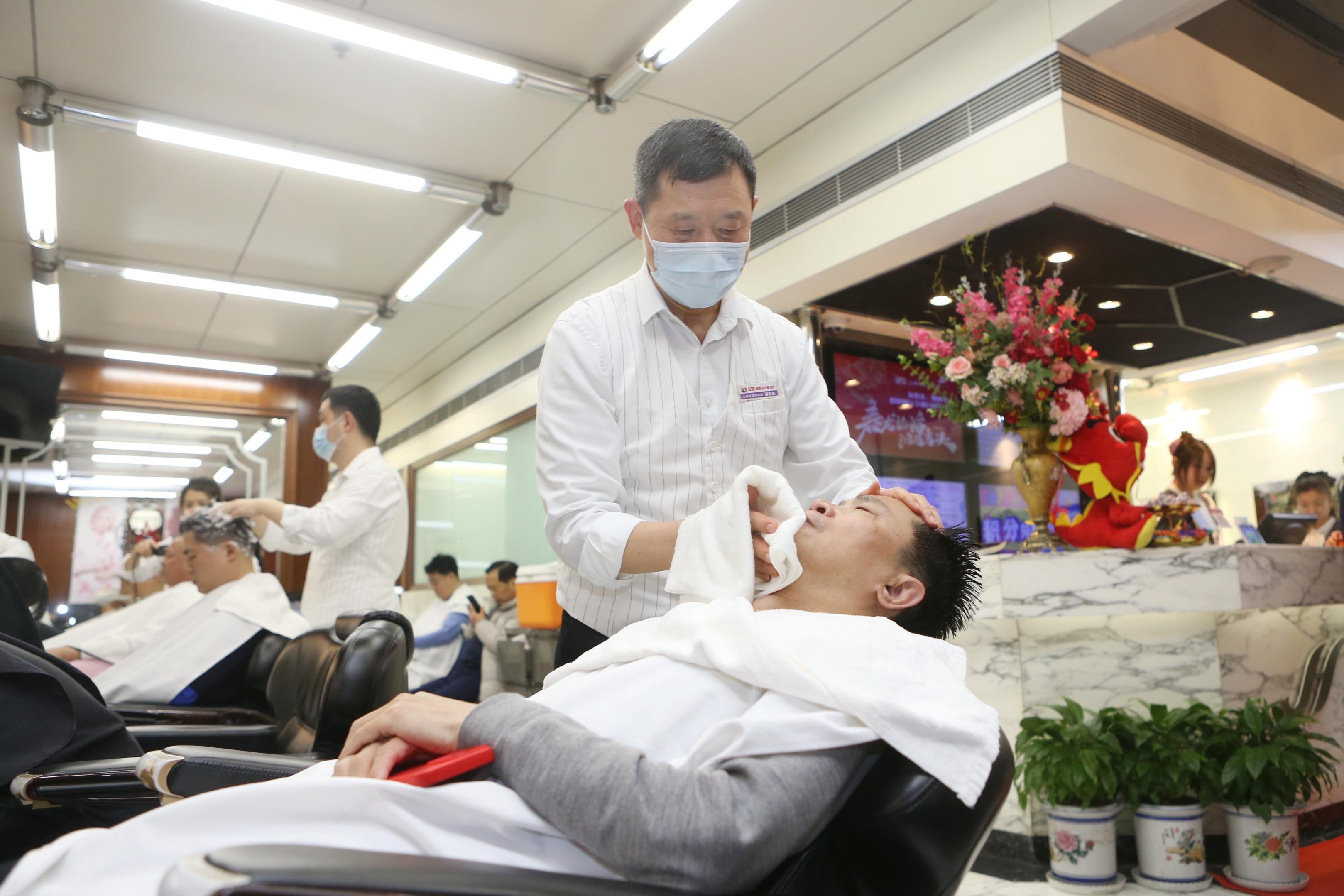 修面的胡天祥正用剃刀为平躺着的顾客刮去脸部的角质和死皮,再用热